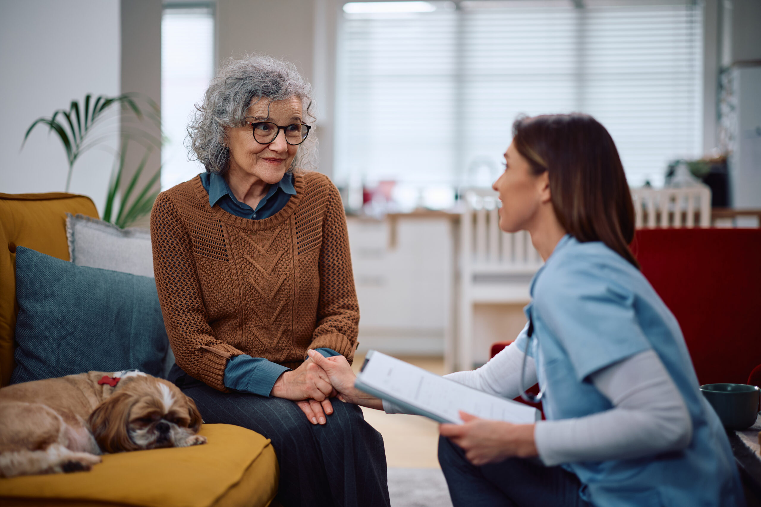 A nurse comforting an elderly woman during a consultation.