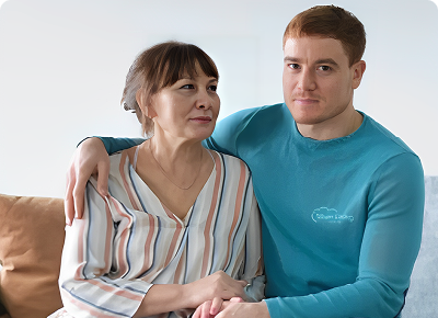 A young man and an older woman sitting close, sharing a warm moment.