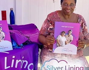 A woman proudly displays Silver Lining care packages for seniors.