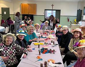 Group of elderly women wearing colorful hats at a festive gathering.