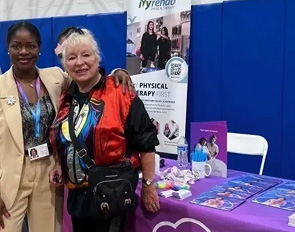 Smiling woman at a physical therapy booth with informational materials.