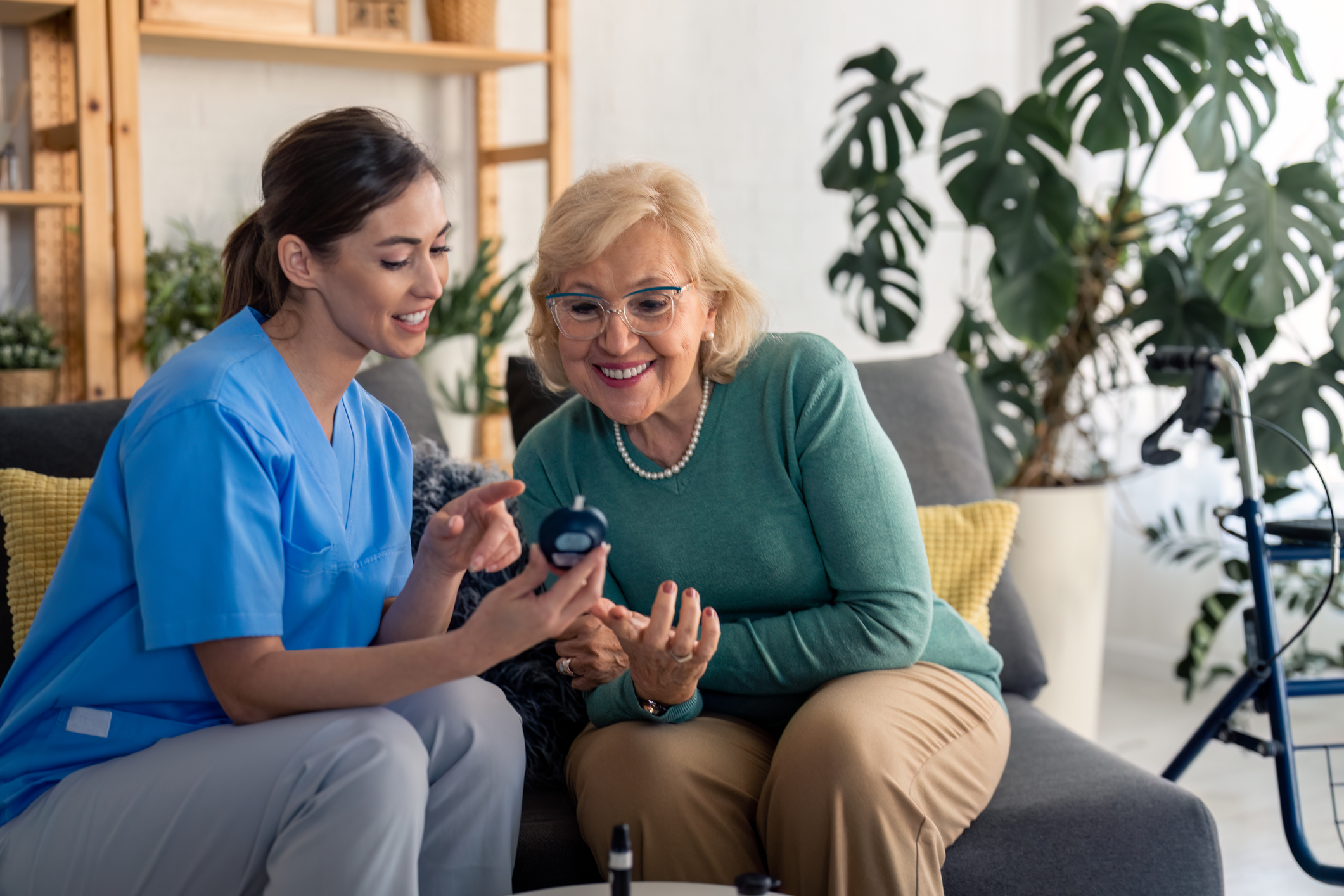A nurse showing a senior woman something on a smartphone with smiles.