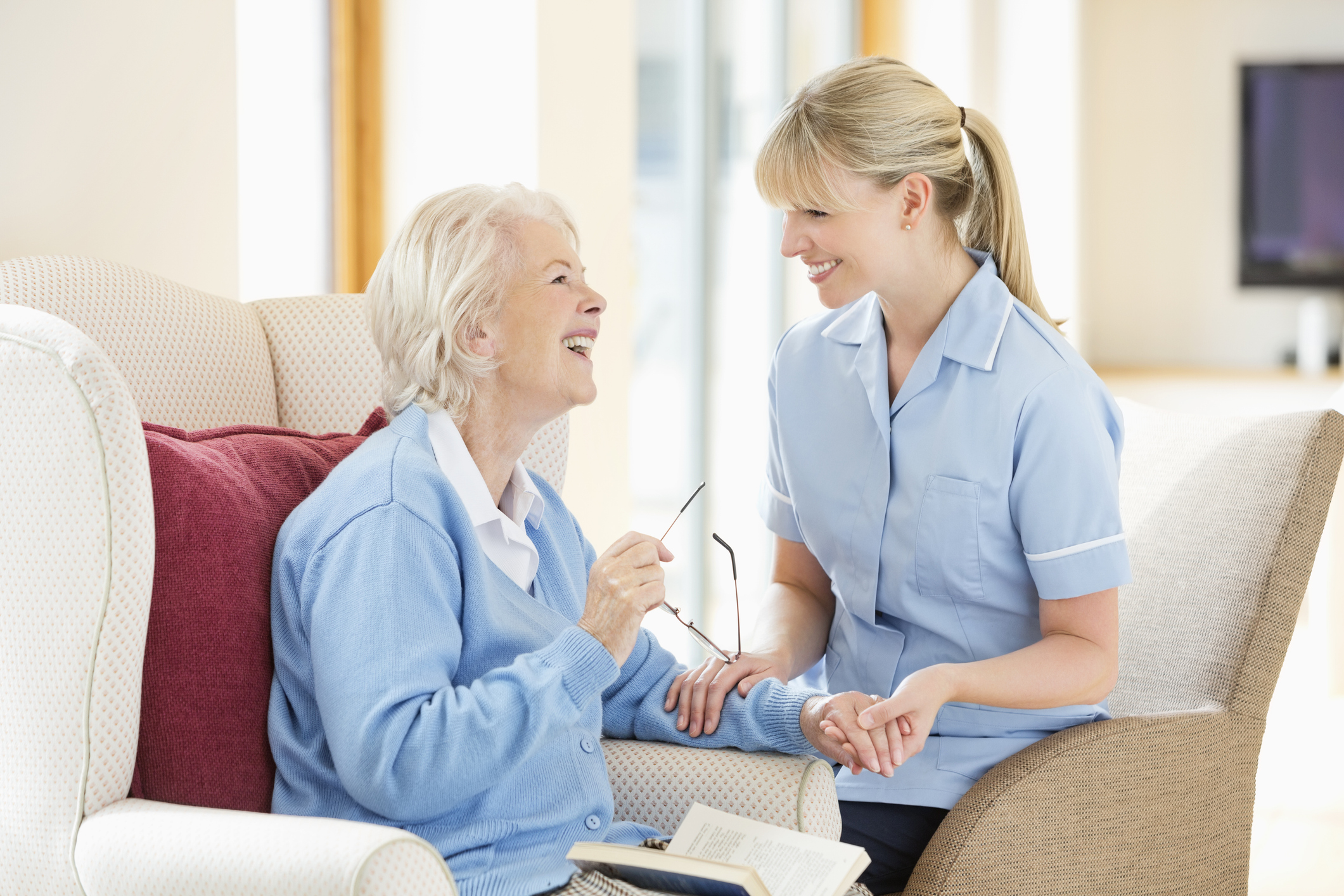 A nurse attentively talks with an elderly woman in a cozy home setting.