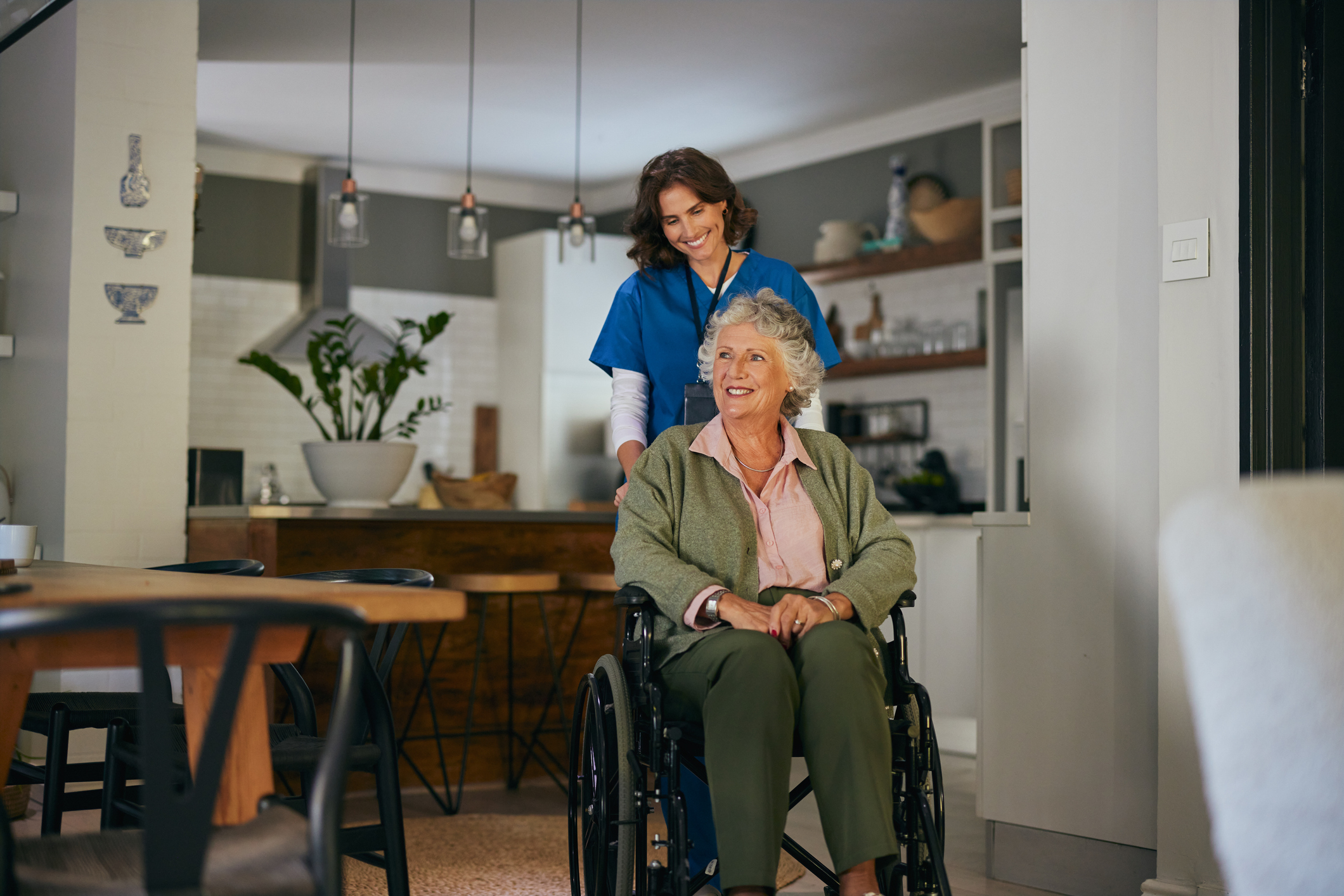 A caregiver assisting an elderly woman in a wheelchair at home.