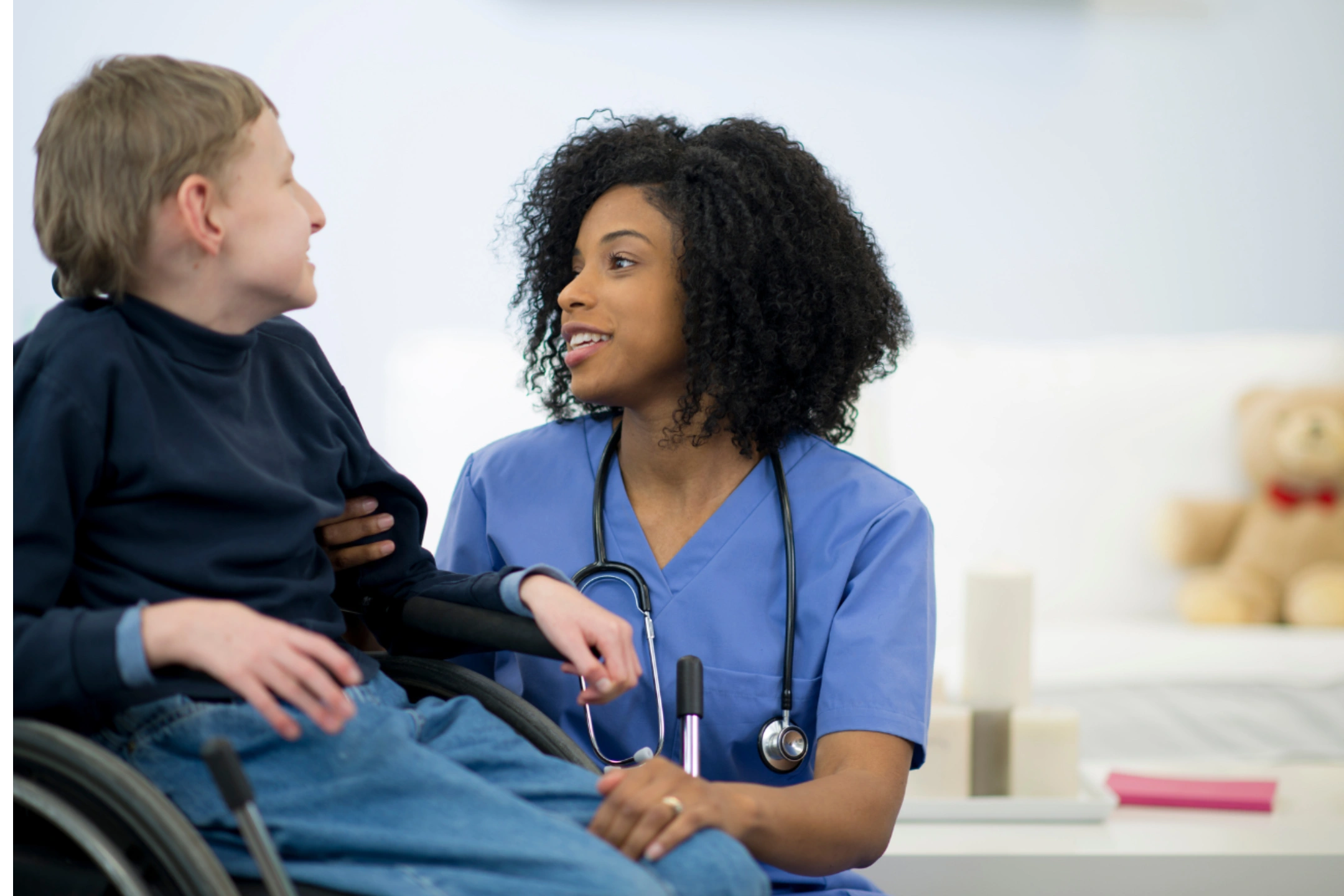 A nurse attentively listens to an elderly patient in a wheelchair.