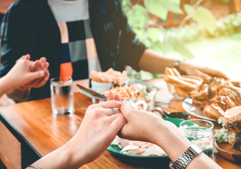People holding hands at a dining table.