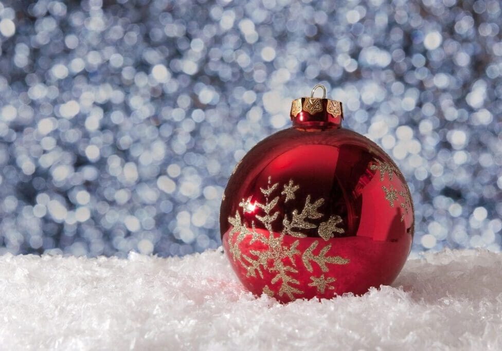 Red Christmas ornament on snowy surface.