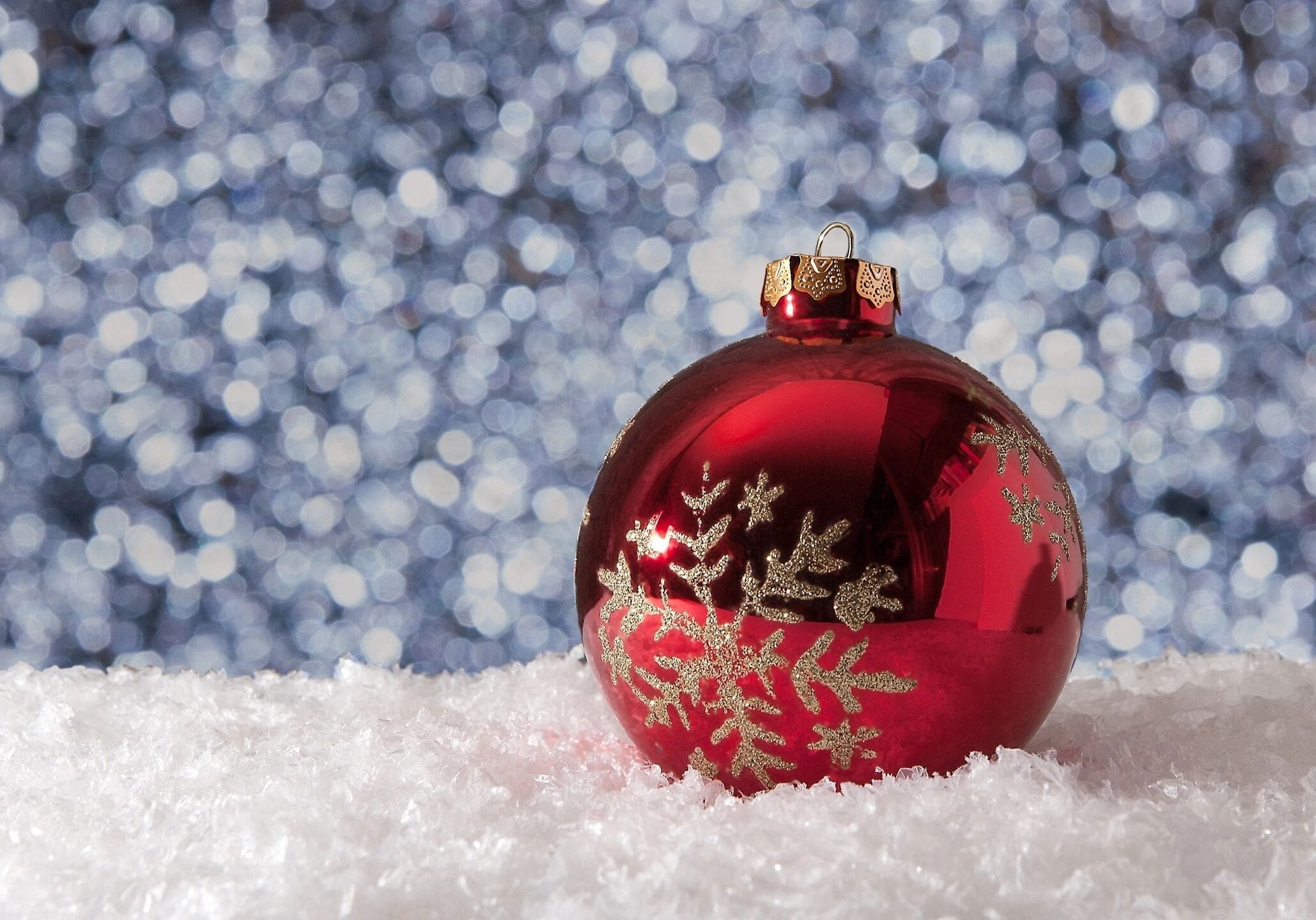 Red Christmas ornament on snowy surface.